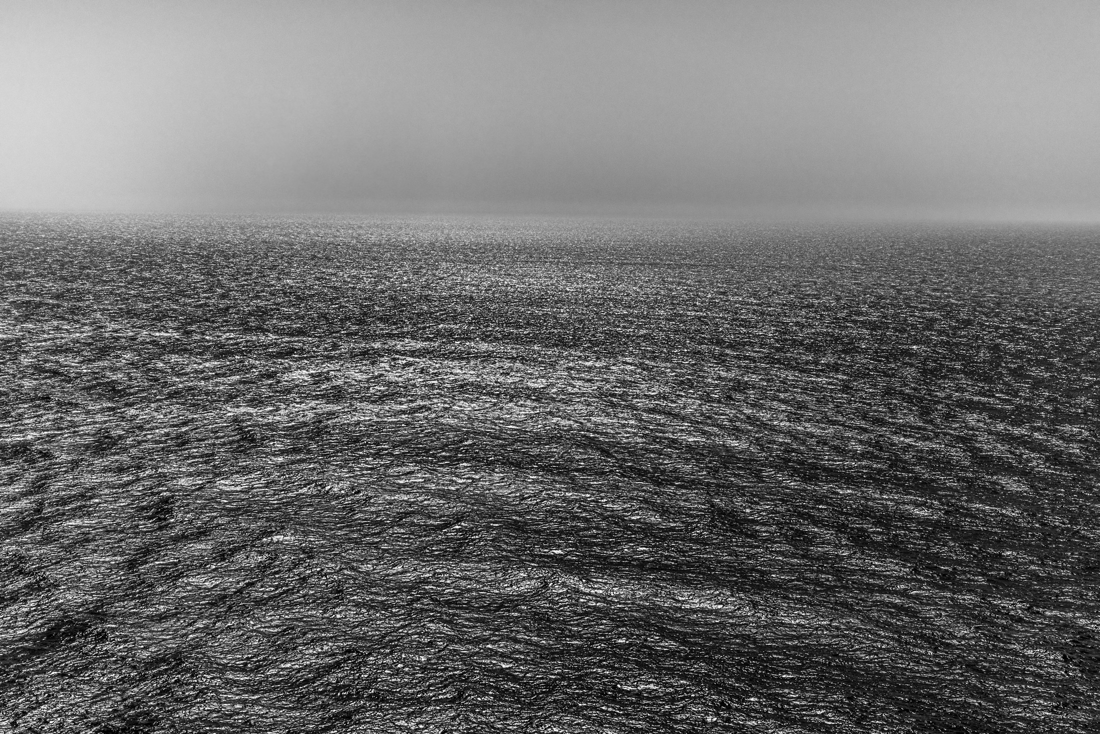 Into the Unknown — The Pacific Ocean stretches toward a hazy horizon, where shifting light and textured waters evoke a sense of mystery.