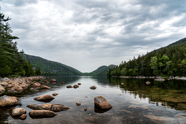 Jordan Pond — A gray morning settles over the boulders of Jordan Pond, with the Bubbles rising beyond