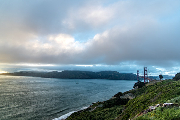 Golden Gate Bridge — The Golden Gate Bridge, small against sea and storm light, seen from the Marin Headlands