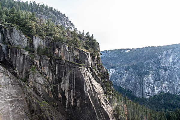 The Granite Edge — Sheer granite falls away into the valley haze in Yosemite National Park, California