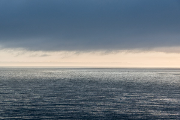 Where Light and Shadow Meet — The waters of San Francisco Bay reflect the fading light of evening beneath a dramatic sky along the horizon.